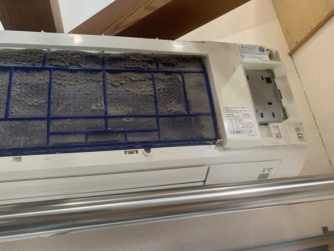 前面パネルを開けた壁掛けエアコン。青いフィルターにホコリが厚く積もっている
